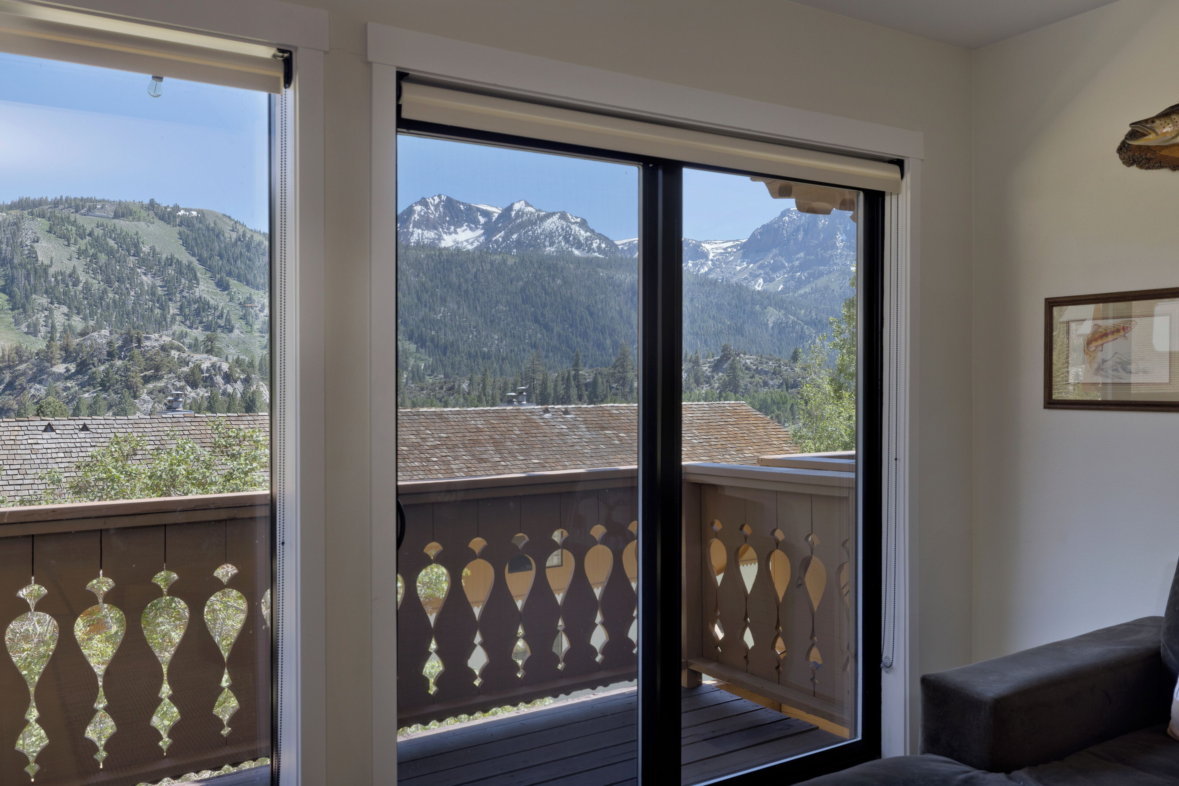A balcony with a view of mountains, a sofa, and a framed picture on the wall.