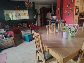 En matplats med ett träbord, stolar, en vas med blommor och en tv.