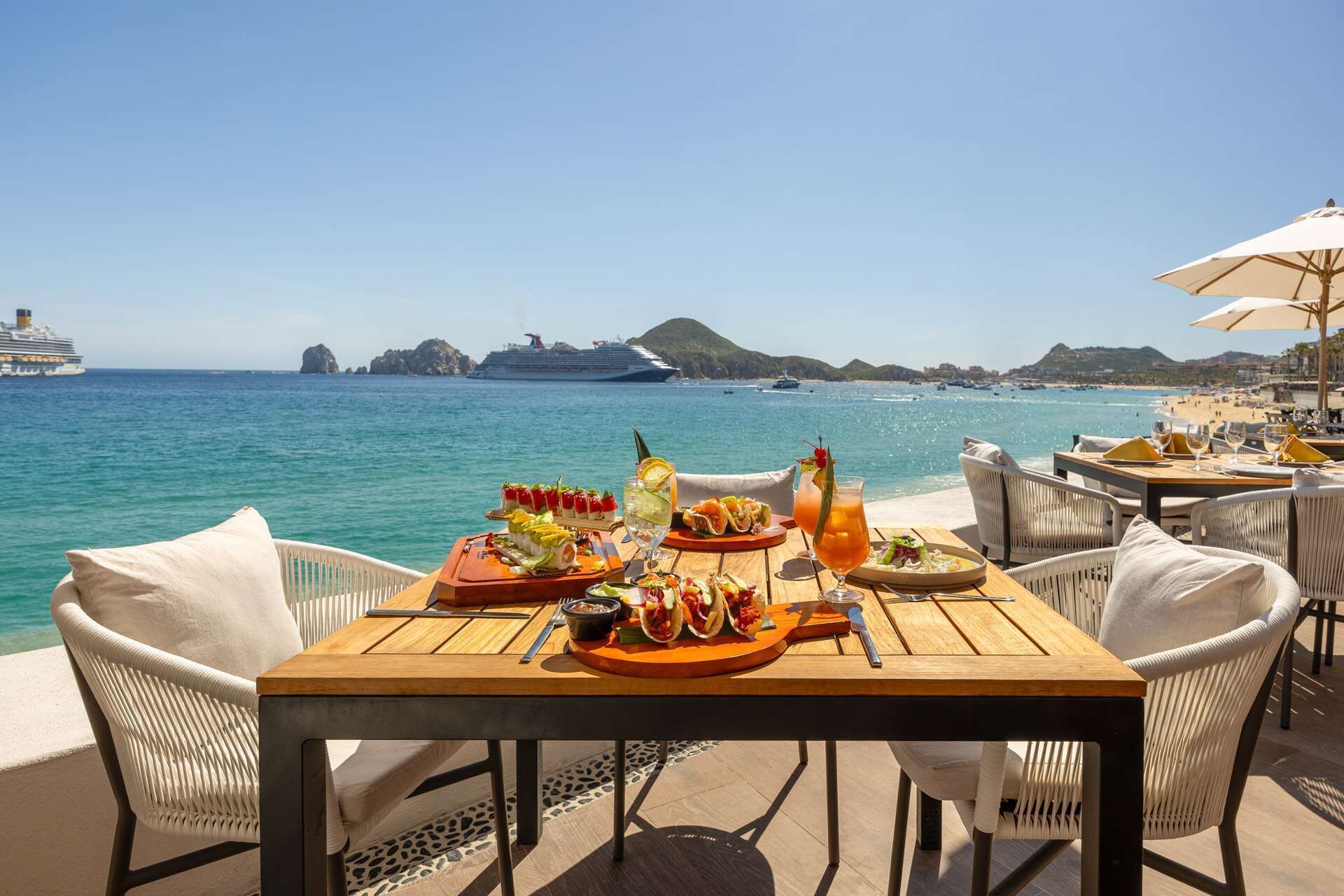 Une table dressée pour le dîner, avec vue sur la mer et des navires en arrière-plan.