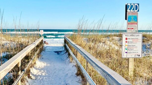 A beach path with a wooden railing, a sign indicating beach warning flags, and a 22D sign. - Sabine 1E Couples Getaway Freshly Remodeled- Brand New Everything! (Pensacola Beach)