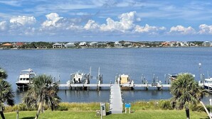 A marina with boats docked, a grassy area, and houses in the background. - Sabine 1E Couples Getaway Freshly Remodeled- Brand New Everything! (Pensacola Beach)