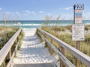 Un sentier menant à la plage et donnant sur l’océan, agrémenté de panneaux d’avertissement et d’un panneau indiquant « 22D ».
