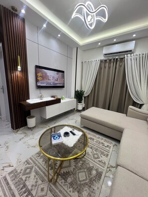 A modern living room with a sofa, a coffee table, a TV, and a patterned rug. - La bela resort apartment (Red Sea Governorate)