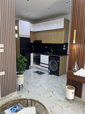 A modern kitchen with a built-in oven, microwave, and dishwasher, a potted plant, and a marble floor. - La bela resort apartment (Red Sea Governorate)