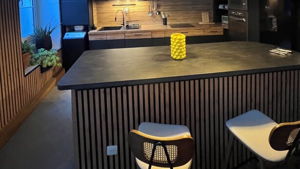 Une cuisine moderne dotée d’un îlot central, de luminaires suspendus et de tabourets de bar.