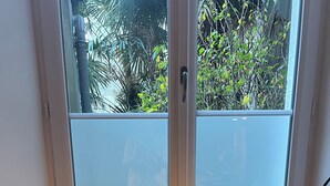 Une fenêtre avec trois plantes en pot posées sur un rebord.