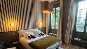 Une chambre à coucher moderne avec un lit, un luminaire suspendu, une chaise et une vue sur l’extérieur.