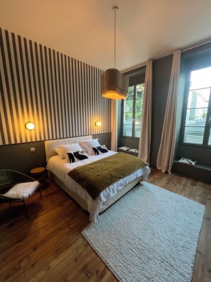 A modern bedroom with a bed, a hanging light fixture, a chair, and a view of the outdoors. - Pau, right in the heart of downtown: Luxury 2-bedroom apartment; Pets allowed (Pau)