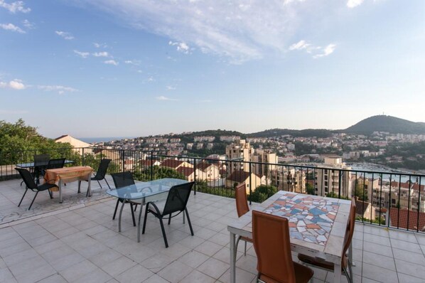 A terrace with outdoor seating, a view of a cityscape, and a distant hill. - Guest House Barbara - Broj 3 - NE Radi!!!!!!!!!!!!! (Dubrovnik)