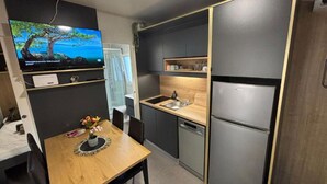 Eine kompakte Küche mit integriertem Kühlschrank, Spüle und einer Essecke mit Tisch und Stühlen.