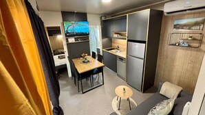 Ein kompakter Wohnraum mit Küchenzeile, Essbereich und Sofa.