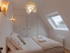 A bedroom with a skylight, a bed with pillows and towels, and a wall-mounted light fixture. - House by Plage de Melon With Garden Retreat (Porspoder)