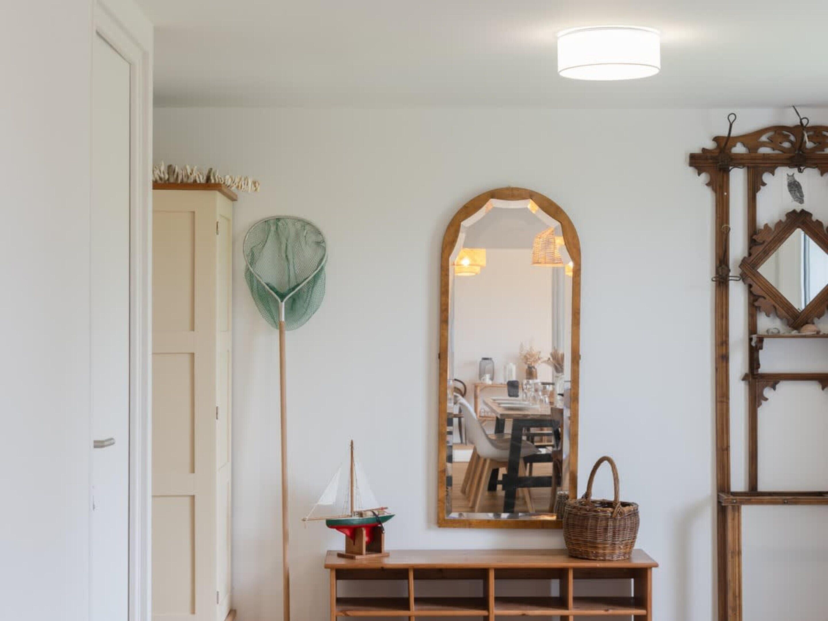 A room with a wooden console table, a mirror, a hanging light fixture, and a door.