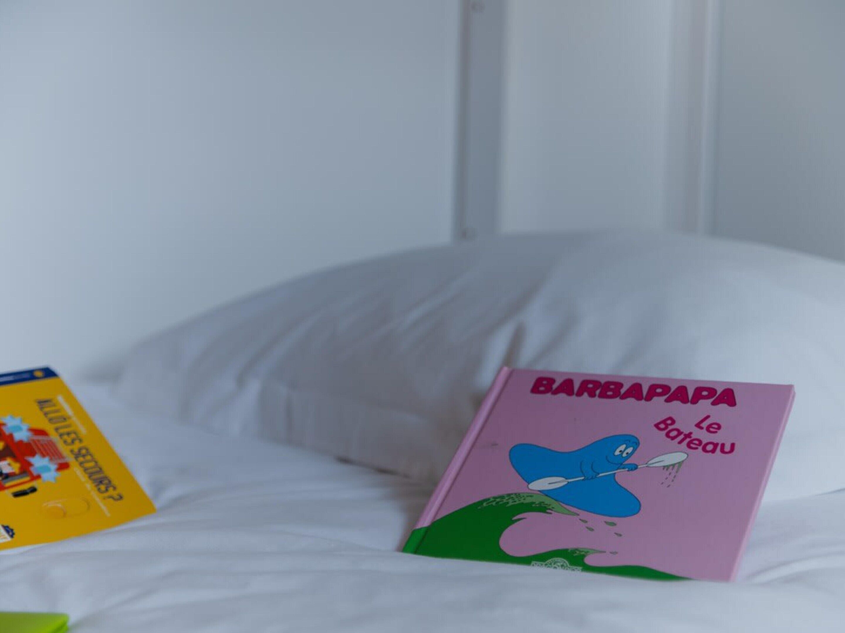 Un letto con un libro rosa intitolato 'BARBAPAPA Le Bateau' e un libro giallo a sinistra.