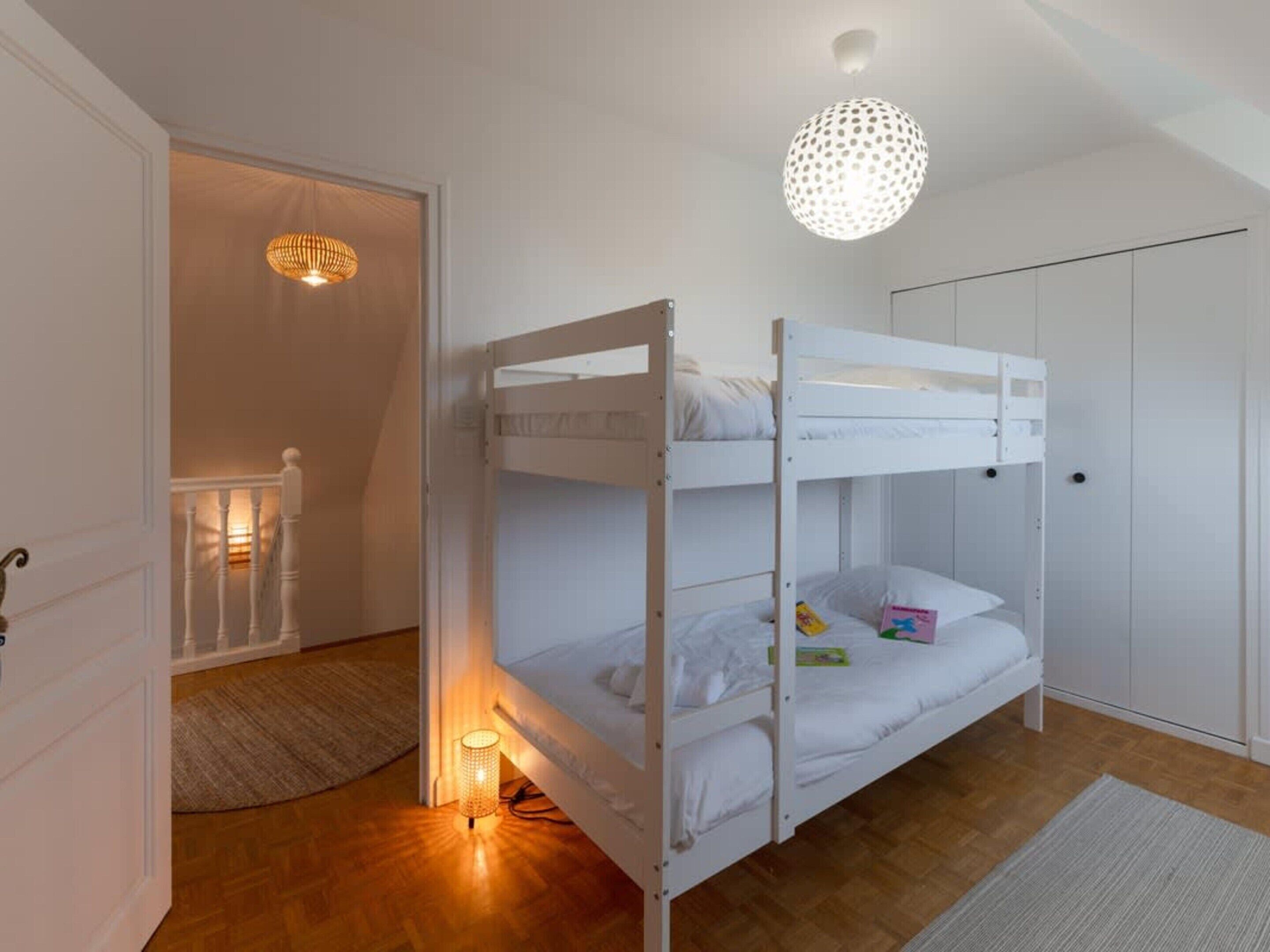 A bunk bed room with a ceiling light, a door, and a small rug.