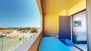 Un balcón con vista a una cancha deportiva, un sofá y una ventana con vista al mar.
