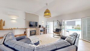 Ein modernes Wohnzimmer mit einer Couch, einem Hängesessel, einem Kamin und einem Fernseher.
