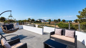 Eine Dachterrasse mit Gartenmöbeln, einer Hängematte und Blick auf das Meer und die umliegende Landschaft.