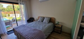 A bedroom with a bed, bedside table, and a view of a pool and garden. - Exceptional villa with a private pool in the heart of Casinca (Penta-di-Casinca)