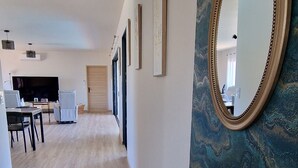Un couloir d’hôtel avec un plancher en bois, un coin repas équipé d’un téléviseur et un miroir fixé au mur.