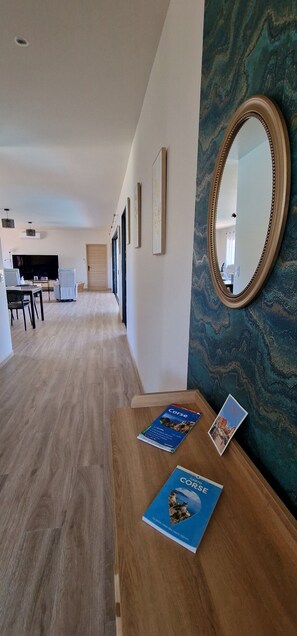 Ein Hotelkorridor mit Holzboden, einem Essbereich mit Fernseher und einem an der Wand befestigten Spiegel.