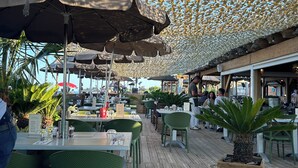 Un espace extérieur aménagé pour les repas, avec un sol en bois, des chaises vertes et des parasols.