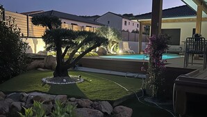Un jardin avec une piscine, un patio couvert et une pelouse bien entretenue.