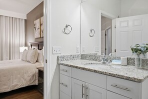 A modern bathroom with a granite countertop, a large mirror, and a white sink. - Beautiful Home, Themed Rooms, Prime Location (Four Corners)