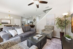 Ein Wohnzimmer mit grauem Sofa, einem gemusterten Sessel und einem Couchtisch.