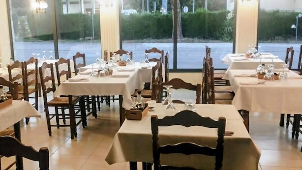 Ein Restaurant mit mehreren Tischen und Stühlen, ansprechend angeordnet in einem großzügigen Raum mit Blick ins Freie.