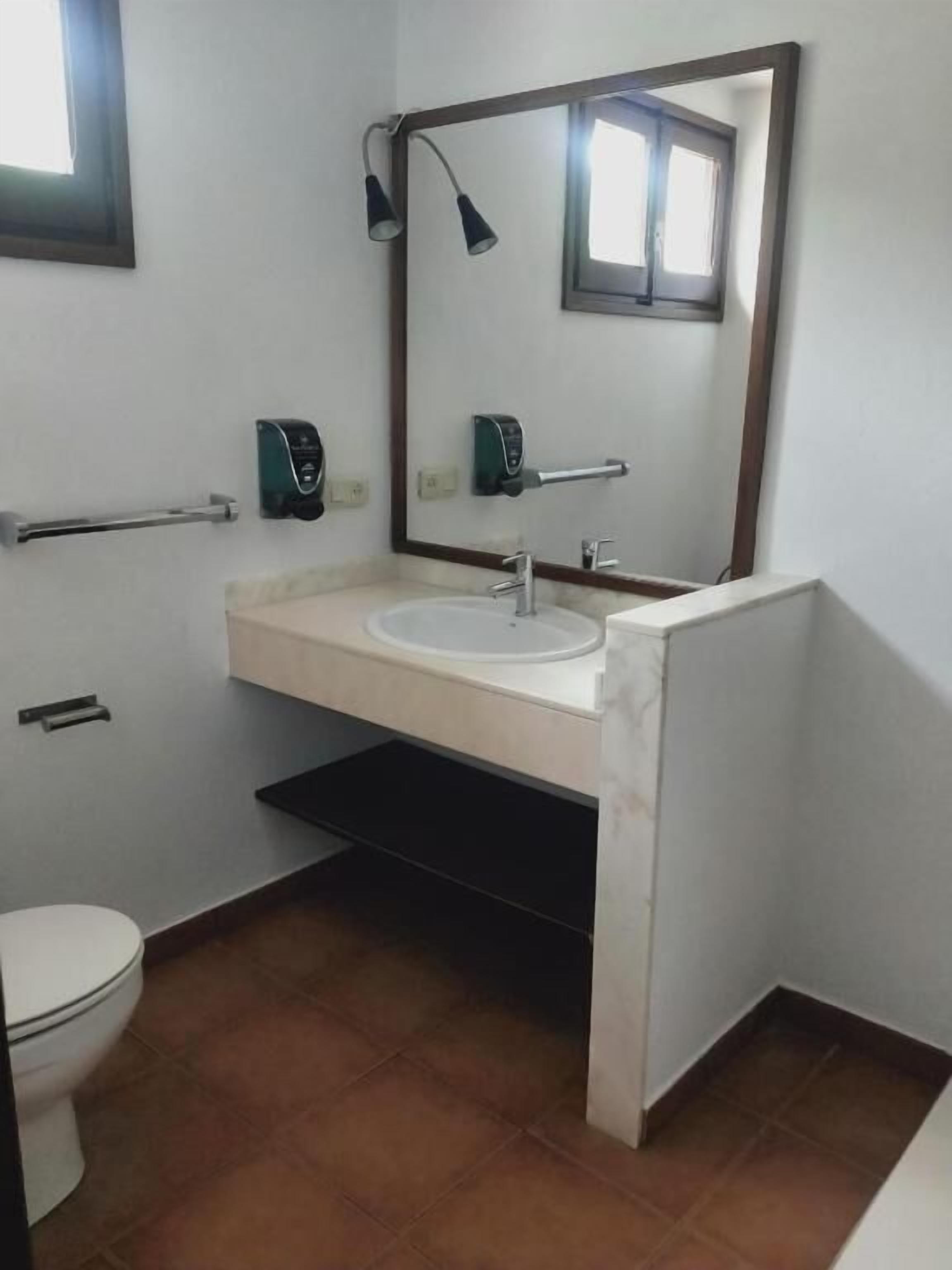 A bathroom with a white sink, a mirror, a towel rack, and a toilet.