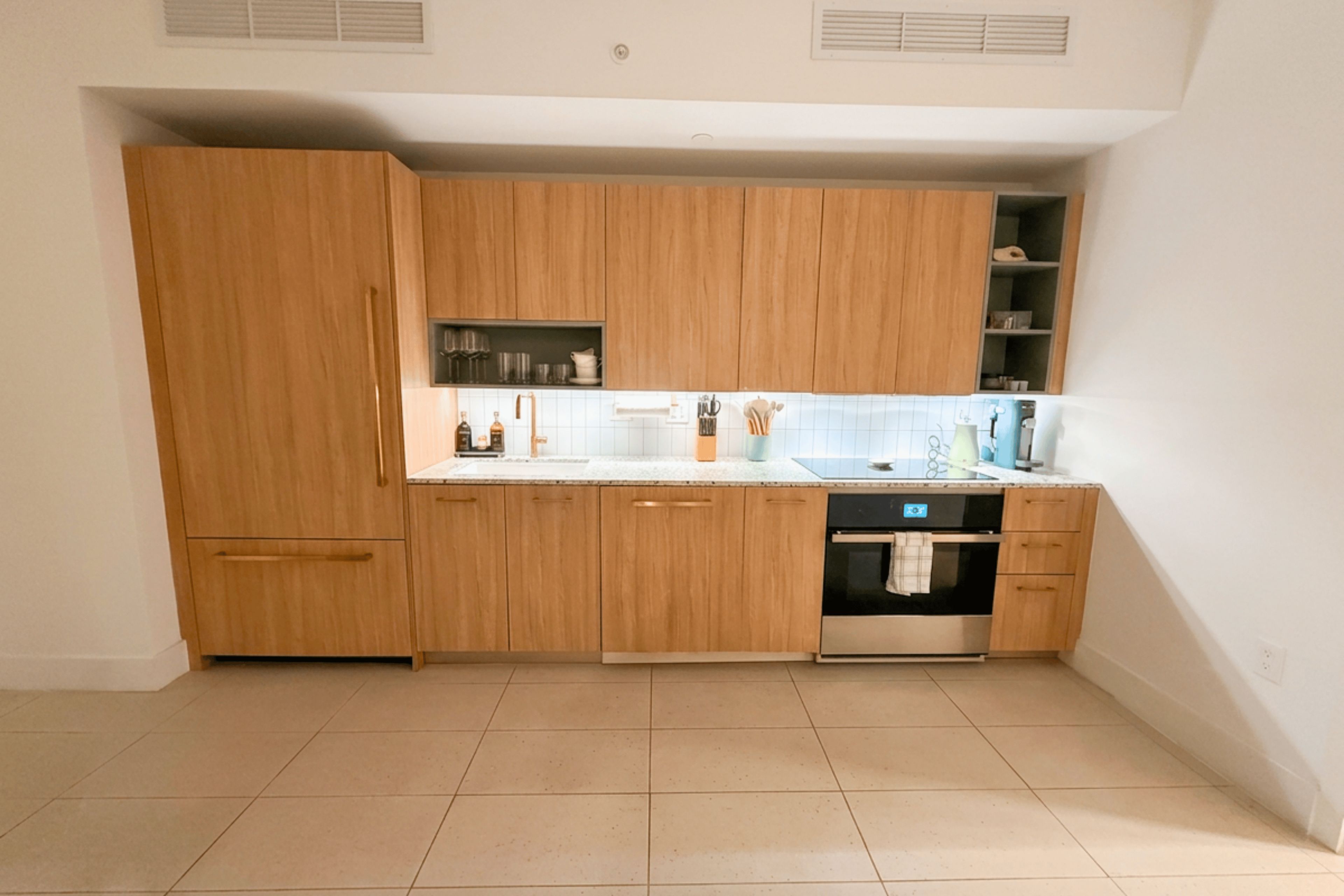 A modern kitchen with wooden cabinets, a stainless steel oven, and a tiled backsplash.
