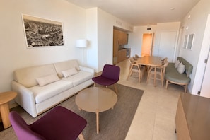 A modern living room with a sofa, a round coffee table, and a dining area with a table and chairs. - Corner Bay-View Stay with Pool and Balcony in Miami G2515 (Miami Beach)