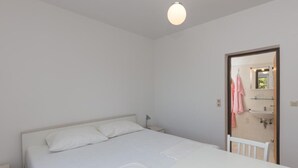 Ein Schlafzimmer mit einem Einzelbett, einem Nachttisch, einer Hängeleuchte und einer Tür zu einem Badezimmer.
