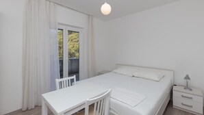 Ein Schlafzimmer mit Bett, Tisch, Stuhl, Nachttisch und Lampe.