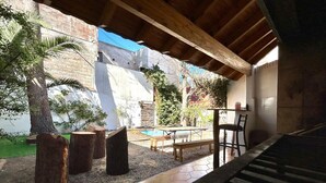 A covered outdoor area with a pool, wooden benches, and a staircase.