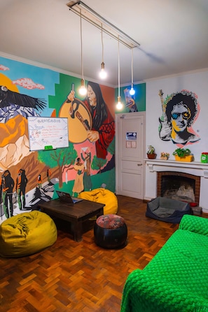 Una habitación con un mural, una pizarra, una chimenea y una cama.