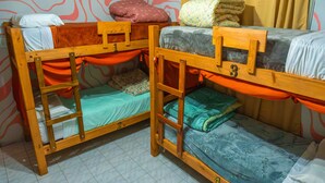 Two bunk beds with wooden frames, a patterned wall, and a curtain.
