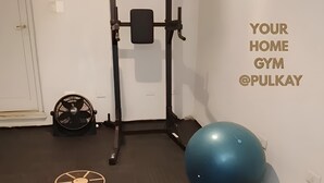 Une salle de sport à domicile équipée d’une barre de traction, d’un ballon d’exercice, d’haltères, d’élastiques de résistance et d’un tapis de yoga.