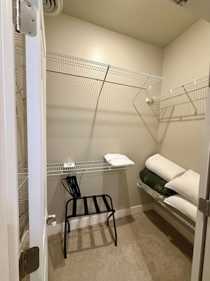 A compact room with a metal shelving unit, a black chair, and a hanging storage area. - Steps from Notre Dame•The Emerald Suite+ Parking (South Bend)