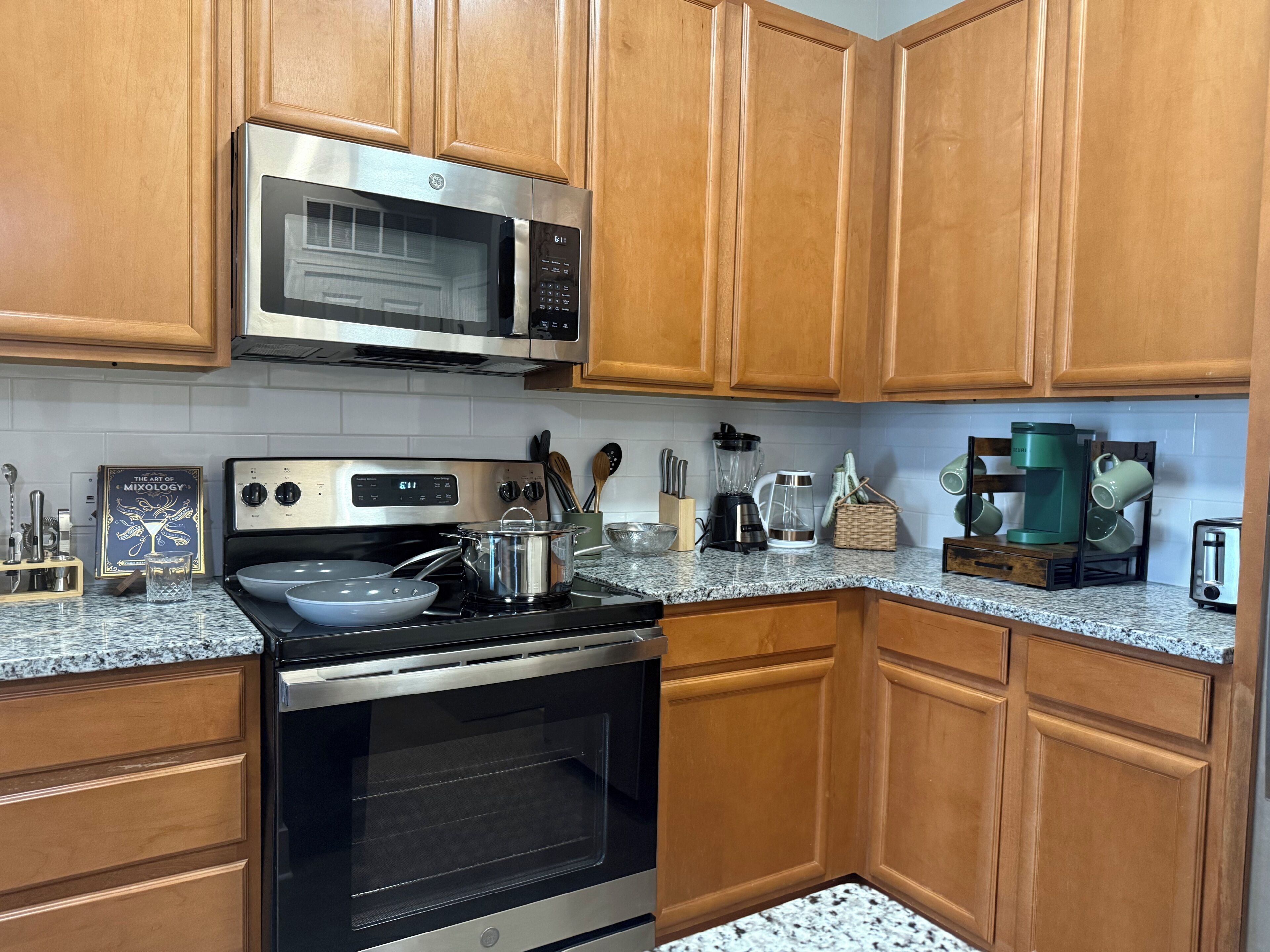 A kitchen with wooden cabinets, a stainless steel microwave, a stove, and a coffee maker.