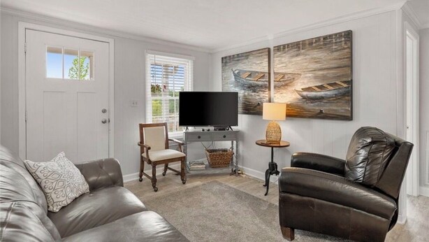 A living room with a television, two armchairs, a sofa, a lamp, and artwork on the wall.