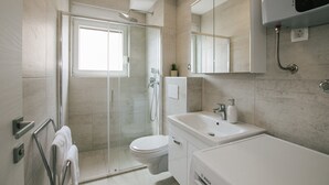 A modern bathroom with a glass-enclosed shower, a white toilet, and a sink with a mirror above. - Spacious Luxury Trogir Apartments - Comfort Two Bedroom Apartment (Trogir)