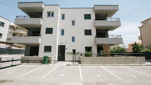 A multi-story building with balconies, a parking lot, and a small garden area. - Spacious Luxury Trogir Apartments - Comfort Two Bedroom Apartment (Trogir)