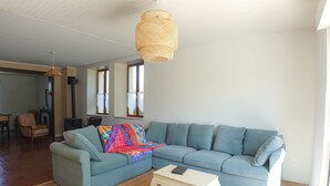 Ein Wohnzimmer mit einem Ecksofa, einem Couchtisch und einer Pendelleuchte.