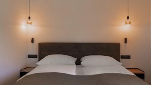 Un lit avec une tête de lit, deux tables de chevet et deux appliques murales.