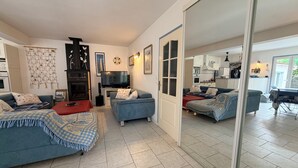 A living room with two sofas, a TV, and a fireplace. - Beach Wood Green (Dolus-d'Oléron)