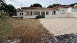 A single-story house with a tiled roof, a gravel driveway, and a small garden area. - Beach Wood Green (Dolus-d'Oléron)