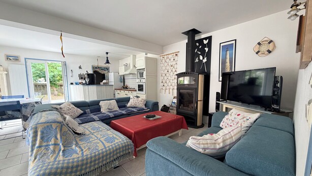 A living room with a sofa, a red table, a TV, and a fireplace. - Beach Wood Green (Dolus-d'Oléron)