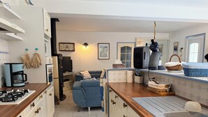 A compact kitchen with a gas stove, a coffee maker, a television, and a blue sofa in the living area. - Beach Wood Green (Dolus-d'Oléron)